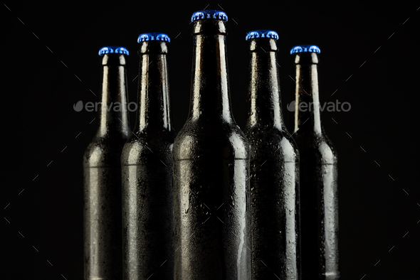 Image of five beer bottles with blue crown caps, with copy space on black background