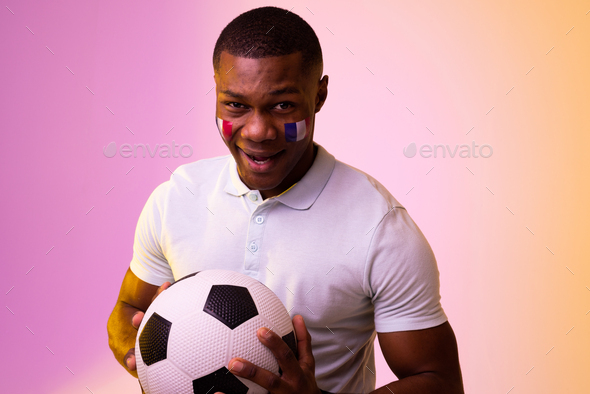 Portrait of happy african american male supporter with flag of france over pink lighting