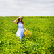 Cute girl in a hat stands in a green field with a bouquet of wild flowers - PhotoDune Item for Sale