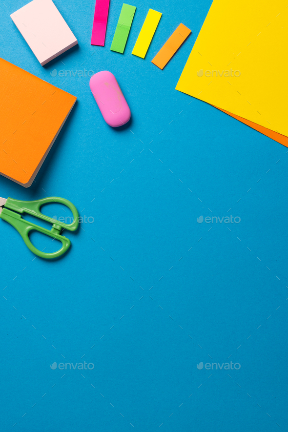Vertical composition of post its, eraser, crayons and scissors on blue  surface with copy space Stock Photo by Wavebreakmedia