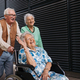 Elderly friends pushing senior woman in wheelchair. - PhotoDune Item for Sale