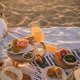 Beautiful tasty picnic with lemonade, fresh fruits and croissants on a beach at sunset. - PhotoDune Item for Sale