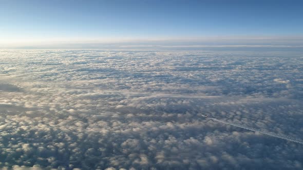 Incredible view from the cockpit of an airplane flying high above the clouds leaving a long white co alt