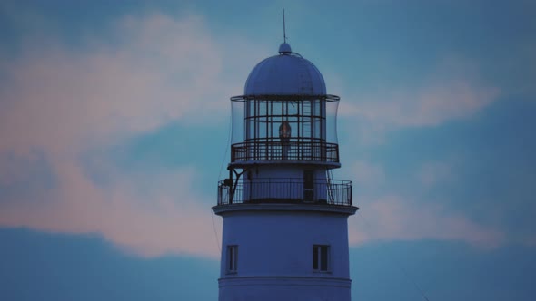 The Lamp of a Large White Lighthouse Shines with Yellow Light