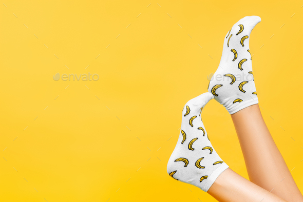 Partial view of female legs in socks with print isolated on yellow