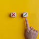 Right and wrong icons on wooden cubes with hand choosing the right icon on yellow background. - PhotoDune Item for Sale