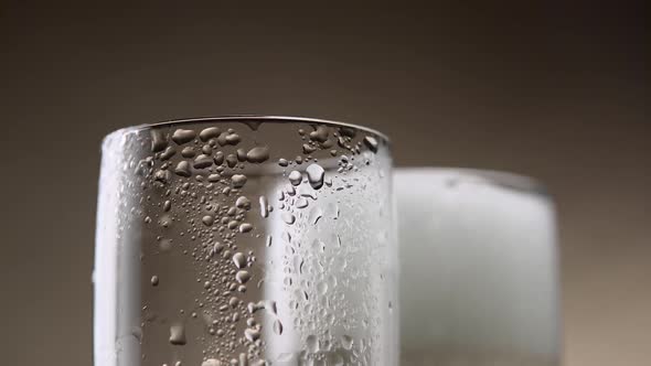 Sparkling Wine Pours From a Green Bottle in Two Steamy Glass. Close Up alt