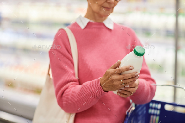 Close up of woman holding bottle of milk in supermarket
