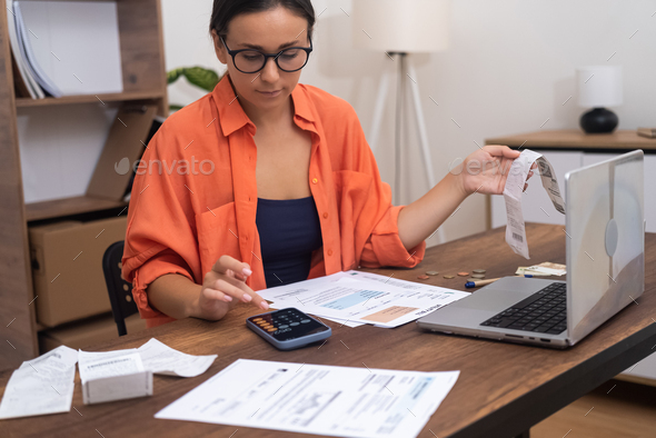 Lady in glasses calculates total amount for utility payments for month of living on mobile phone