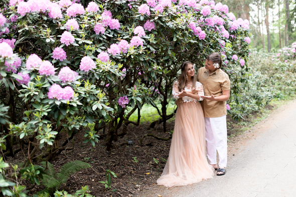 Sensual pregnant couple in blossom garden. Future parents in blooming rhododendron park. - Stock Photo - Images