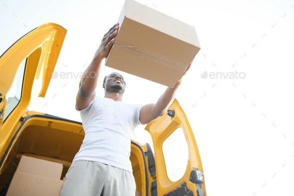 Low Angle View Of Loader Man Standing Near The Van Holding Cardboard Box