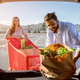 Happy young indian couple packing shopping bags with fresh food into the car trunk, view from the - PhotoDune Item for Sale