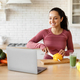 Cheerful fitness lady looking at laptop cooking salad at kitchen - PhotoDune Item for Sale