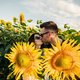 Beautiful couple is kissing in sunflowers field at sunset. A man and a woman in love walk in a field - PhotoDune Item for Sale