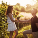 Beautiful couple having fun in sunflowers field. A man and a woman in love walk in a field with sun - PhotoDune Item for Sale