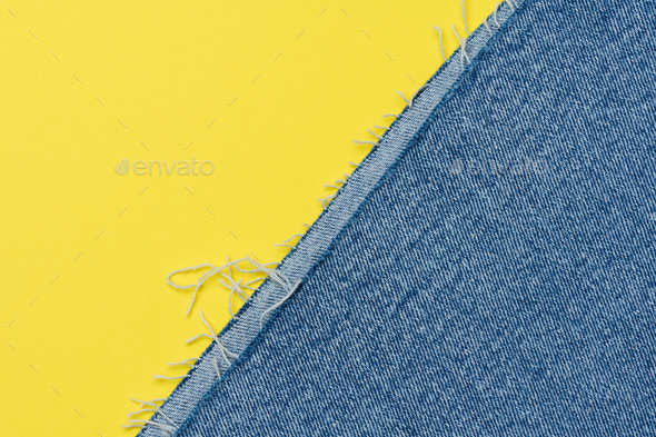 Torn edges of blue jeans on a yellow background - Stock Photo - Images
