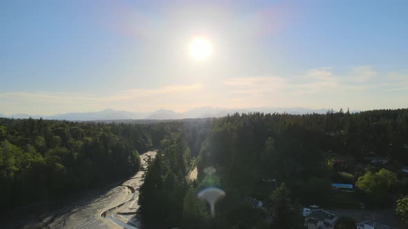 Small bridge dam, distant mountains, green trees small low tide river creek flying toward the sunset alt