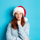 Winter holidays and Christmas Eve concept. Silly redhead girl with freckles, wearing santa hat and - PhotoDune Item for Sale