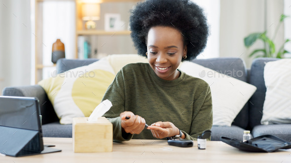 Happy African American woman using a glucose monitoring device at home. Smiling black female checki