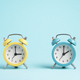 Two alarm clocks of blue and yellow colors. Concept of winter and summer time. - PhotoDune Item for Sale