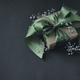 Paper gift box with olive green ribbon tied in a bow, small flowers, black background.  - PhotoDune Item for Sale