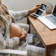 Unrecognizable pregnant woman sitting at the table looking at her baby&#39;s ultrasounds at home - PhotoDune Item for Sale