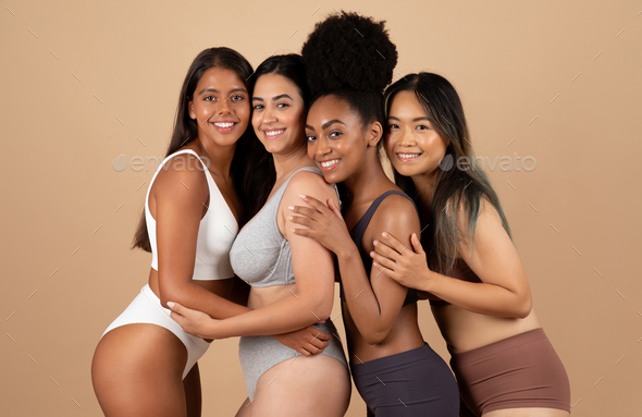 Cheerful millennial latin, arab women in underwear hugs, isolated on beige  background Stock Photo by Prostock-studio