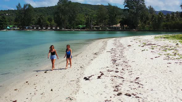 Cheeky teenage girls walking along the sandy coast in Thailand. Summer break on the tropical island alt