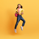 Pretty teen girl going to school, jumping on yellow background - PhotoDune Item for Sale