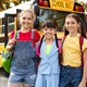 Portrait Of Three Happy Girls Posing Outdoors Near School Bus Together - PhotoDune Item for Sale