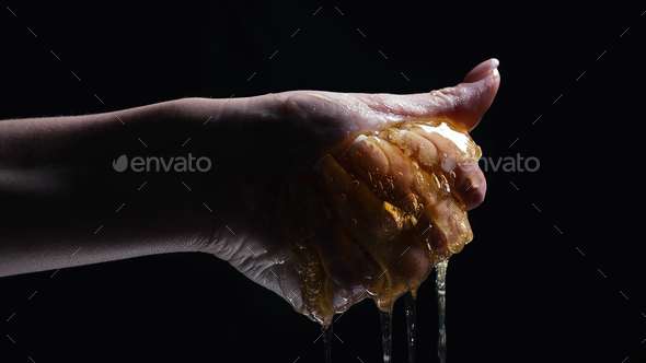 Woman hand squeezes honeycombs full of honey. Dripping,pouring tasty sweet fluid