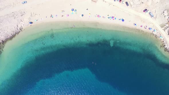 Flying above umbrellas and people on isolated beach of Pag island, Croatia alt