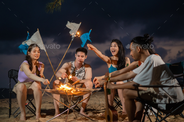 Group of Asian young man and woman having party on the beach at night. A