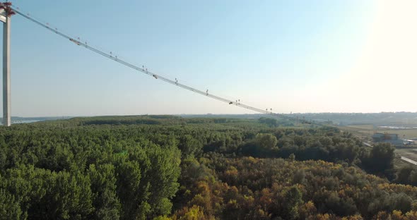 Main Cable Of Braila Bridge Crossing Over The Vast Green Forest In Romania. aerial alt
