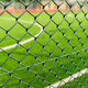Through the chain-link fence, a blurred soccer field emerges, where passion for the game and dreams - PhotoDune Item for Sale