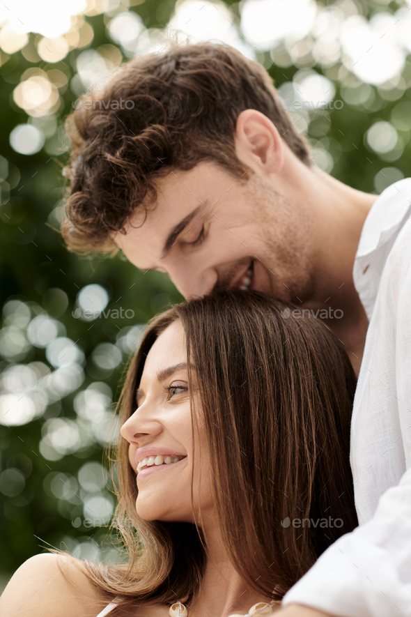 couple bonding and trust, cheerful man kissing head of beautiful woman