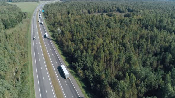 Convoy of Trucks Ride on the Highway Near Forest, Logistic Transportation, View of the Road From alt