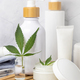 Opened cream jar with white lid near green cannabis leaves close up, CBD cosmetic mockup - PhotoDune Item for Sale