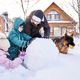 A family builds a snowman out of white snow in the yard in winter. - PhotoDune Item for Sale