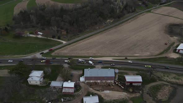 Drone view over farm in valley with rescue vehicles at scene of an accident.