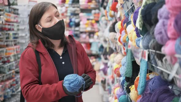 Woman in a Mask and Gloves Buys Chenille Yarn for Knitting