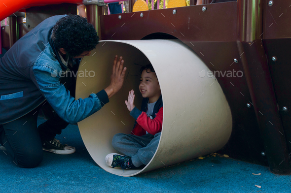 Latin Venezuelan father and son together playing in tunnel in public park games