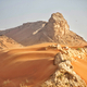 Blowing red desert sand in arid wilderness setting with rocks and rock formation in hot afternoon  - PhotoDune Item for Sale