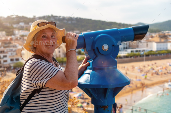 Happy elder woman looking through coin operated binoculars