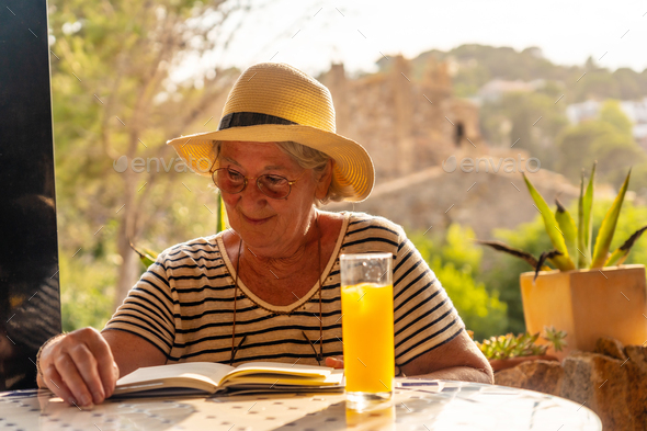 Happy elder woman reading a book in an outdoor terrace