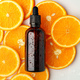 Glass bottle of essential citrus oil on oranges background - PhotoDune Item for Sale