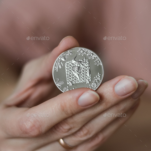 The person holds in his hand a commemorative coin dedicated to the year of the bull