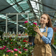 A young girl takes care of indoor plants in a greenhouse. - PhotoDune Item for Sale