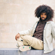 young afro man sitting on a step of a square looking at the camera - PhotoDune Item for Sale