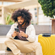 young afro man using mobile phone sitting on a square step with yellow suitcase - PhotoDune Item for Sale